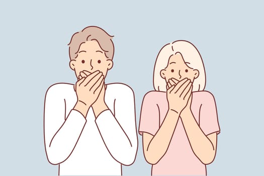 Frightened couple covers mouths after seeing unexpected incident and looks at screen showing shock emotions. Frightened man and woman in casual clothes feeling shock after hearing breaking news