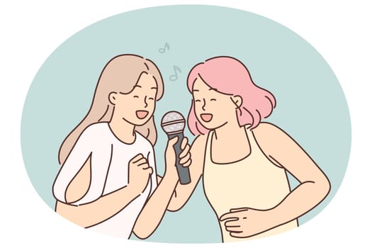 Two women sing song in karaoke at house party. I get positive emotions from musical leisure. Young cheerful girls with microphone enjoy singing in karaoke club or professional recording studio