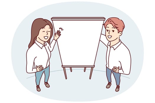 Man and woman office employees stand near empty flipchart carry out business presentation. Top view of guy and girl pointing with hands at sheet of paper for advertising services